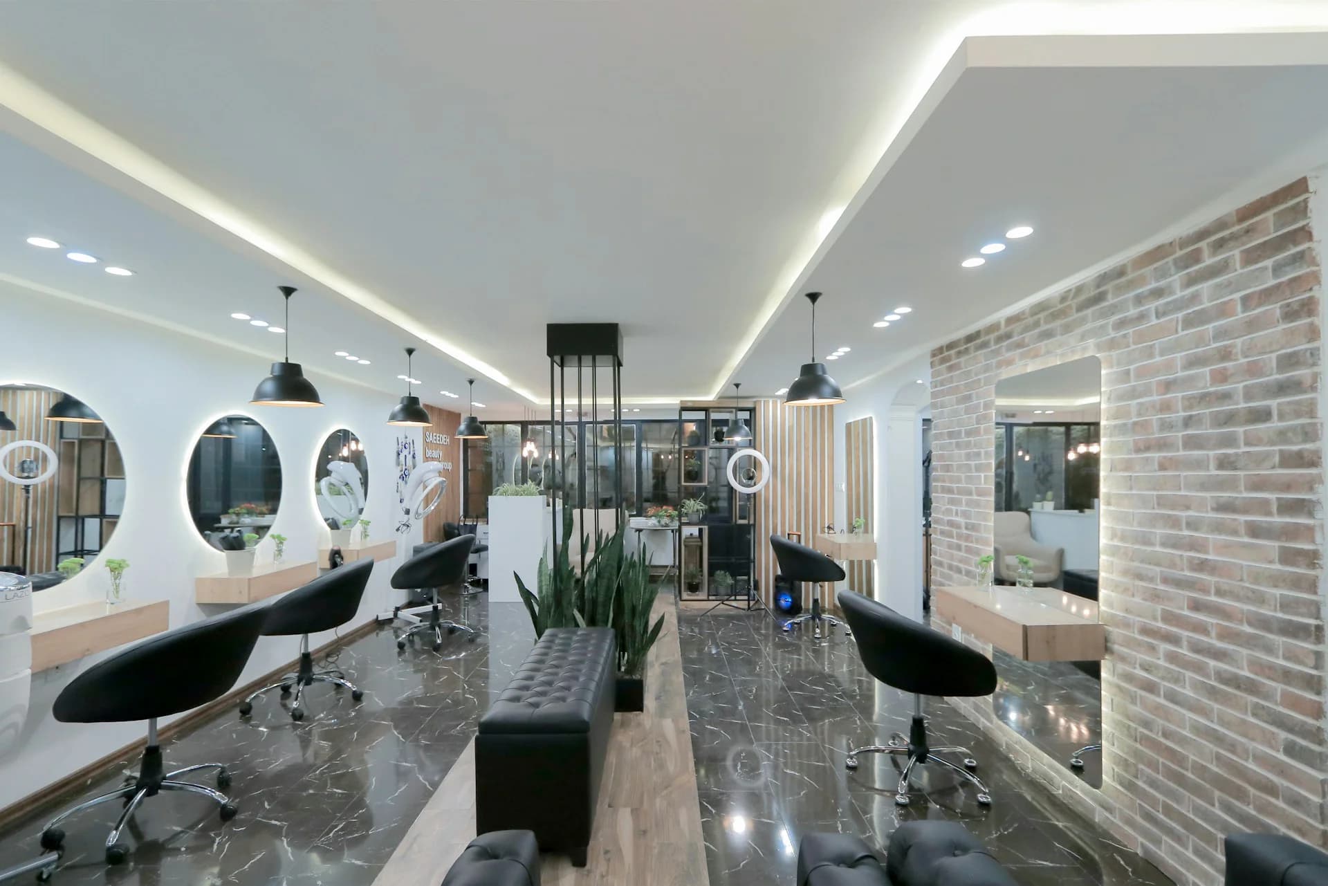 Interior de una peluquería moderna con tocadores, espejos iluminados y sillones negros