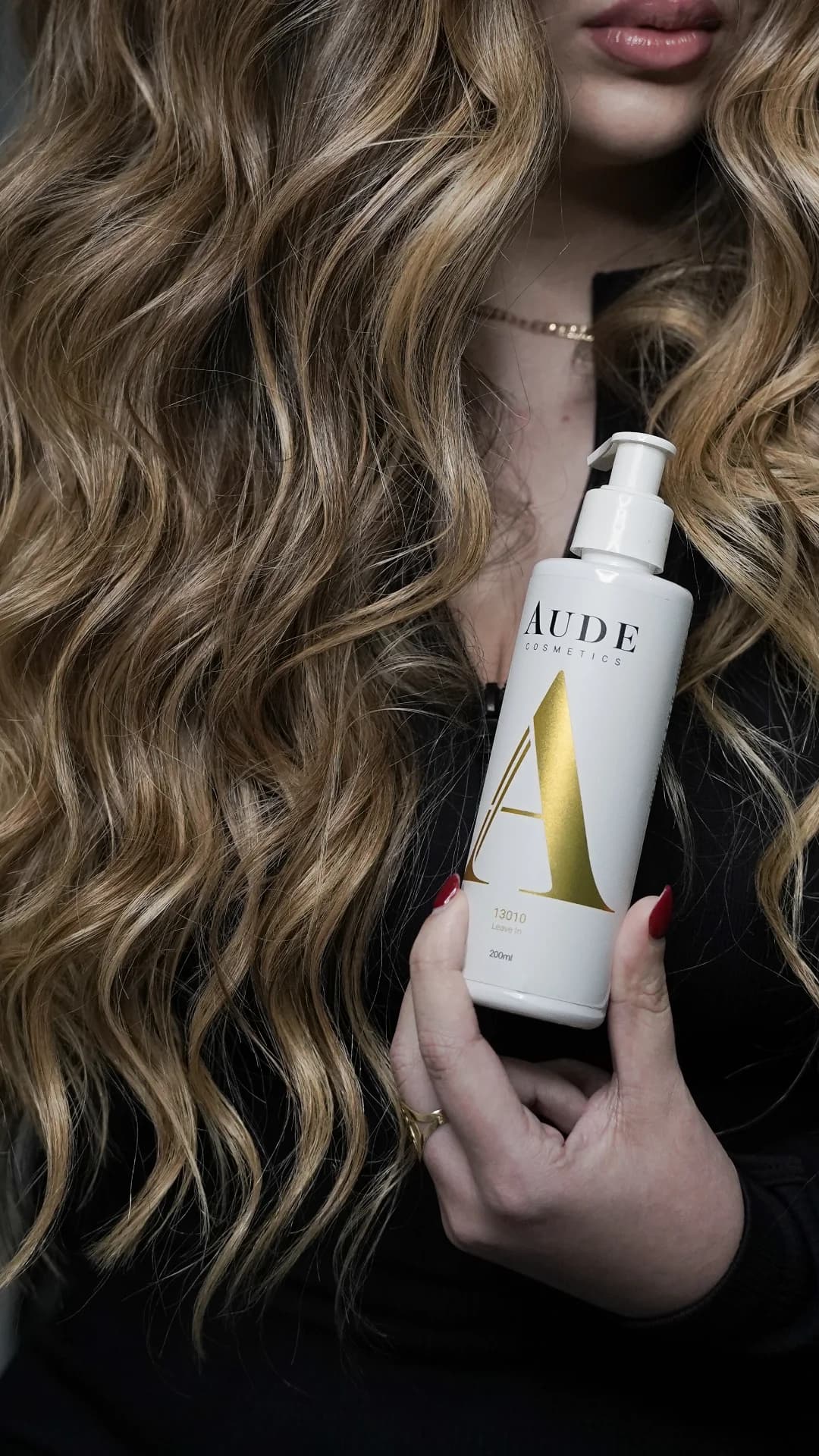 Mujer con el cabello largo y ondulado sujetando el Leave In 13010 de Aude Cosmetics de 200 ml