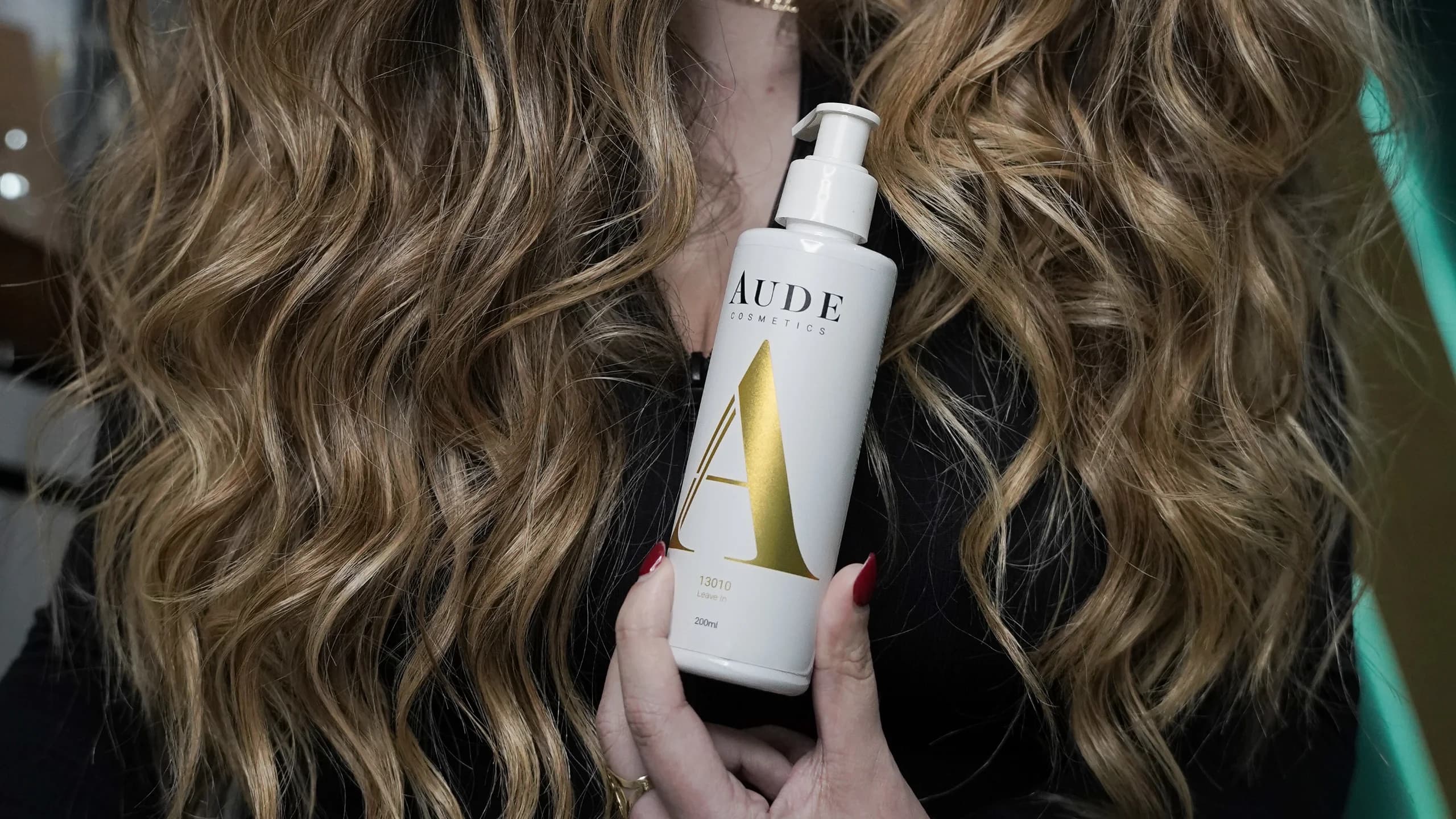 Mujer con el cabello largo y ondulado sujetando el Leave In 13010 de Aude Cosmetics de 200 ml