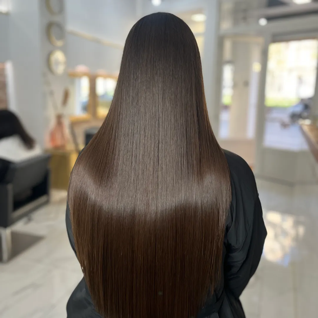 Back view of long, straight brown hair with an intense shine in a salon