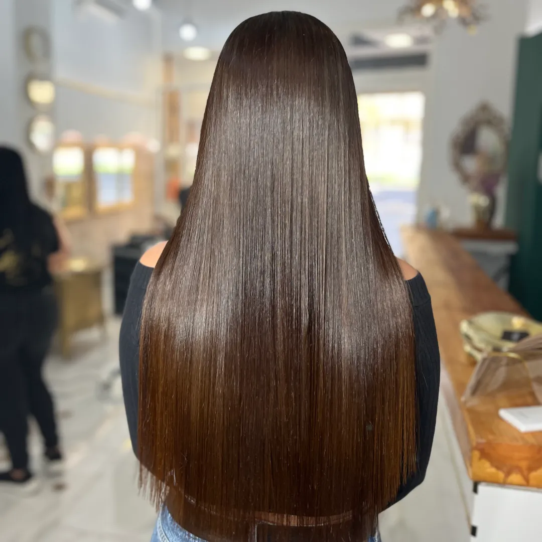 Back view of long, straight brown hair with even ends, in a salon
