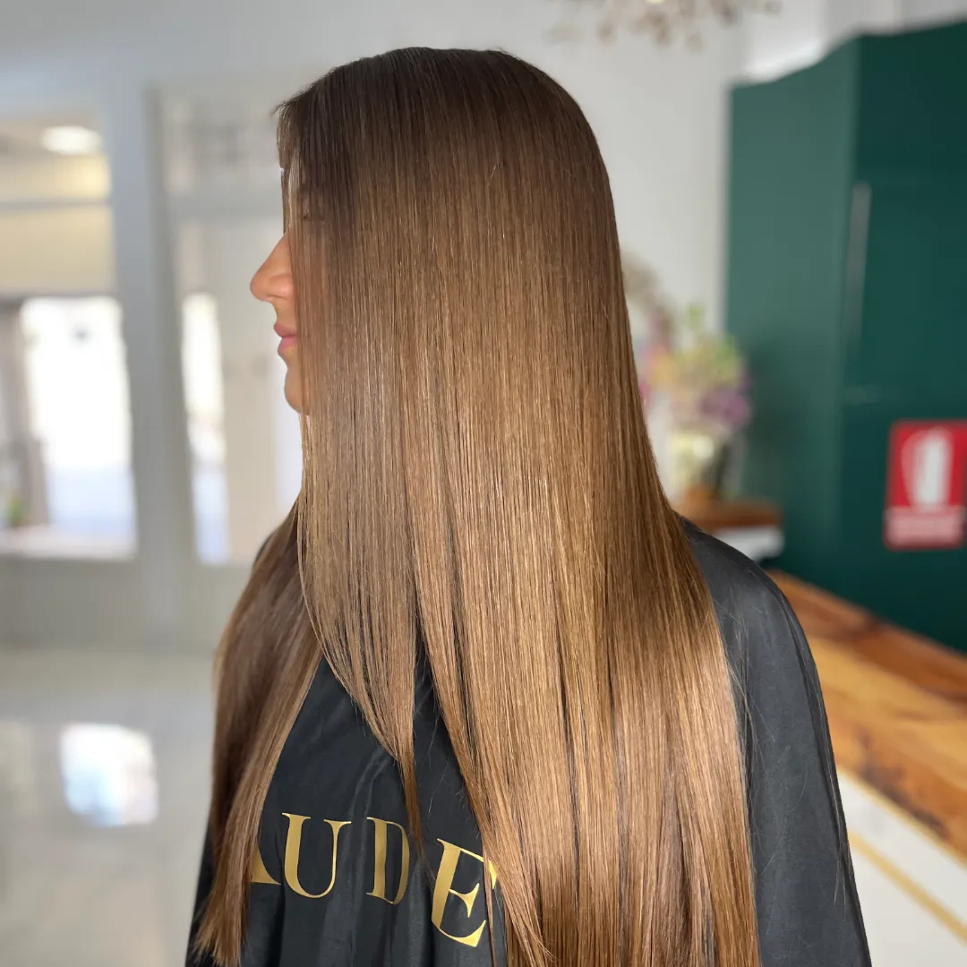 Long, straight light-brown hair over a black Aude cape, seen in profile