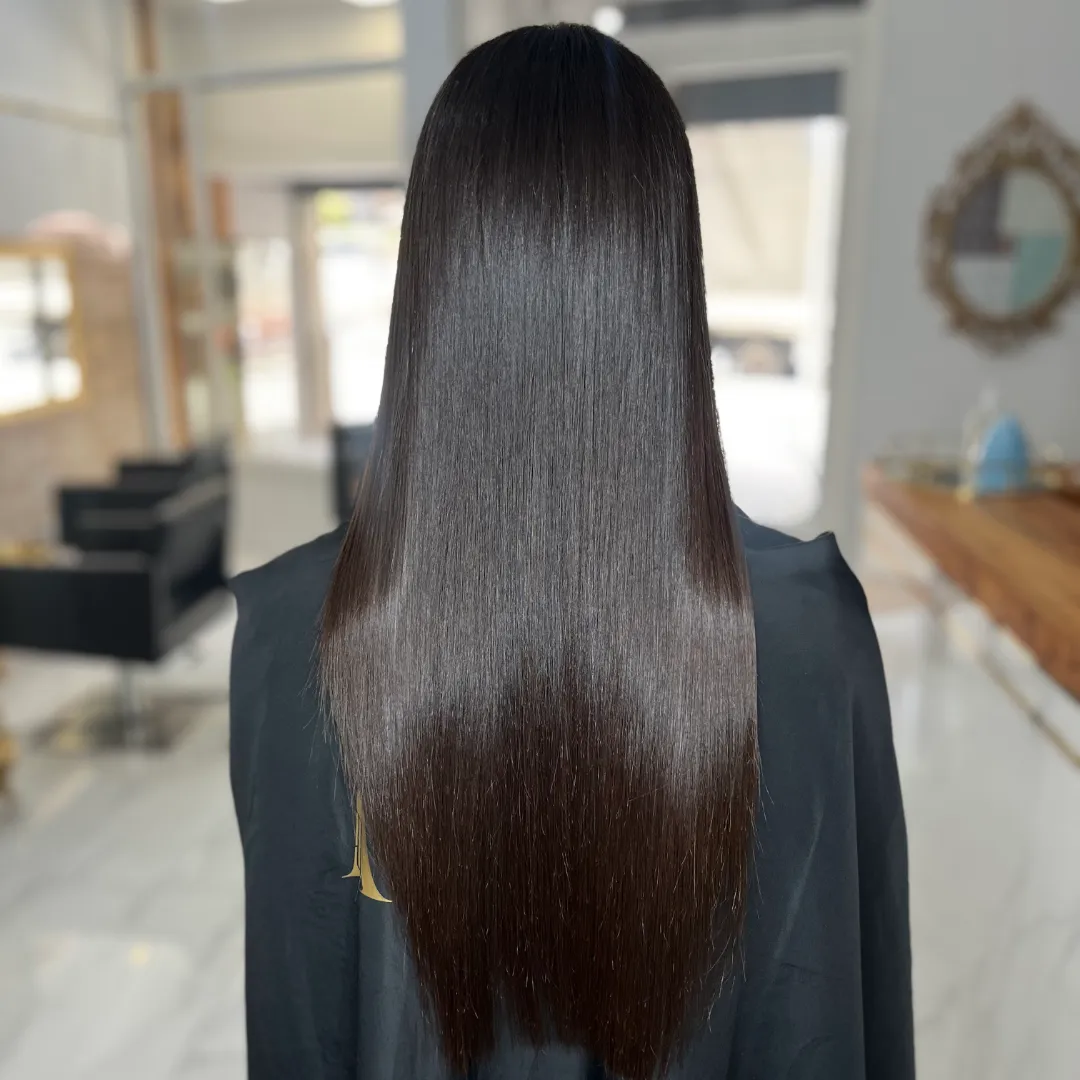 Back view of very long, straight dark-brown hair over a black Aude cape