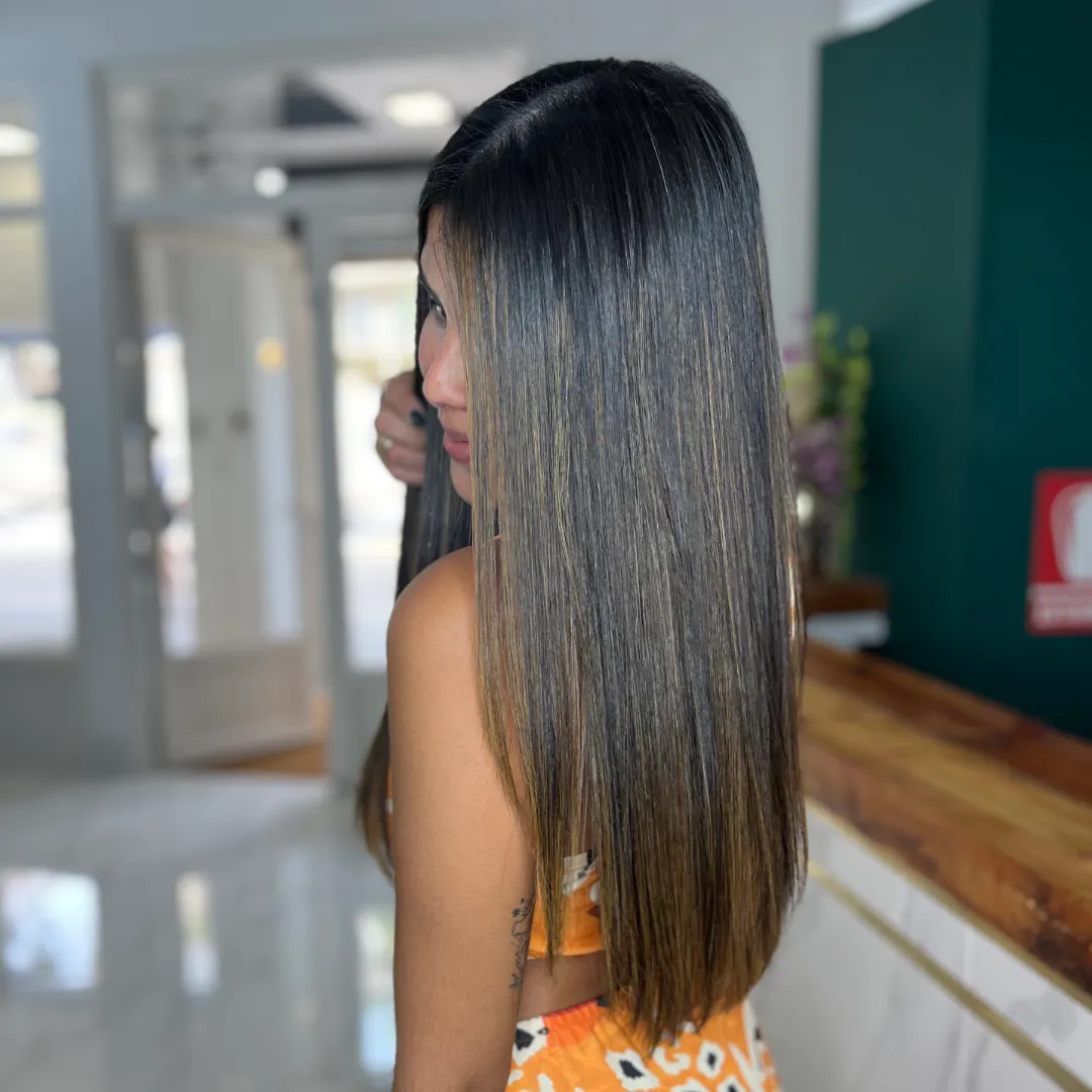 Straight black hair with lightened highlights, seen in profile in a salon