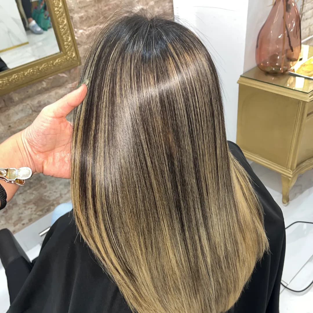 Top view of brown hair with blonde highlights, straight and shiny, styled in the salon