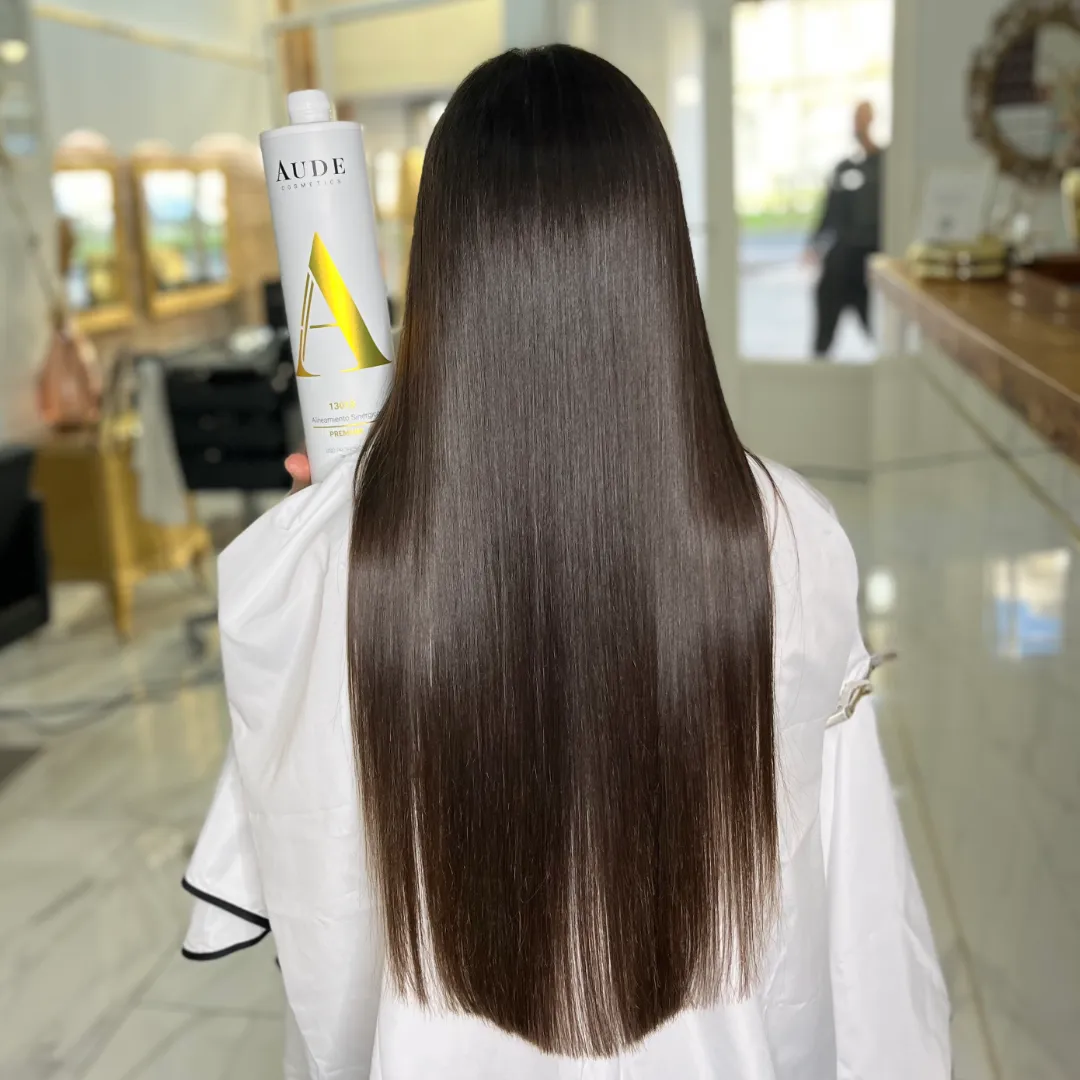 Back view of long, straight brown hair next to the Aude Cosmetics Synergic Alignment bottle in a salon